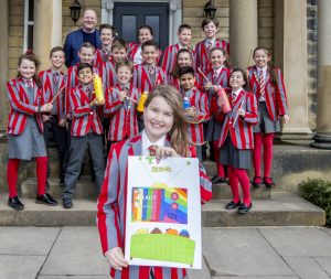 Ilkley Primary pupil, winner of Ilkley Carnival Cover Competition, poses with Year 6 classmates outside school