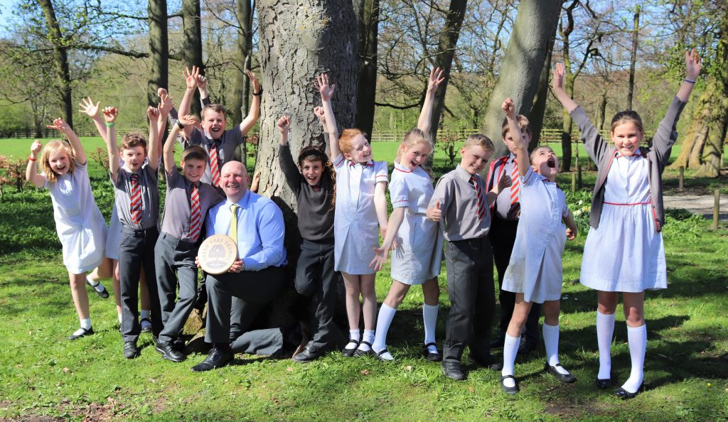 Excited pupils celebrating their Gold Award with Headteacher Mr Martin