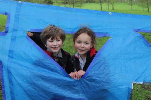 Two schoolchildren smiling during their forest schools lesson