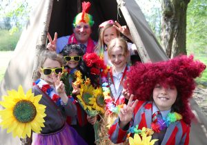 Headteacher and pupils dressed in festival wear promoting school music festival