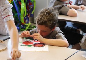 Boy threading a needle to stitch his artwork