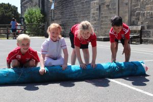 Primary school children rolling out felt on the playground