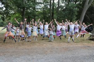 Group shot of all children jumping in the air in their handmade kilts