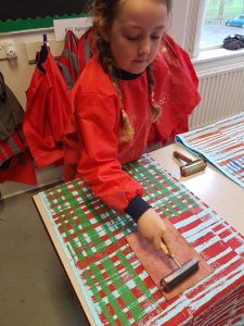 Primary school pupil printing with lino printing block onto fabric