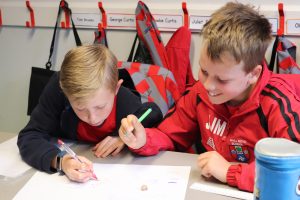 Ghyll Royd School boys look closely at a fossil and write down what animal they think it is