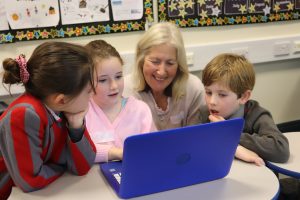 Grandparents' Day - a Ghyll Royd grandmother helping a group of children on the computer