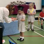 Ilkley Nursery child smiling as she is presented with a leaving gift at her nursery graduation