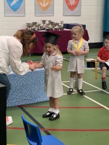 Ilkley Nursery child smiling as she is presented with a leaving gift at her nursery graduation