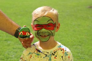 Ilkley Primary school child with face paint and matching painted pebble