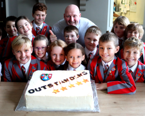 Children gather around a lit chocolate cake.